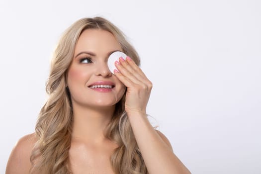 A woman is gently and carefully applying various skincare products using a soft cotton pad to achieve a radiant look
