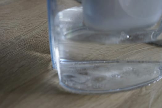 water in filter jug on wooden table kitchen clean health drinkable bacteria ecology recyclable . High quality photo