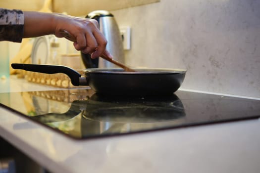 A chef is stirring delicious food in a pan on a modern stove, creating a delightful meal