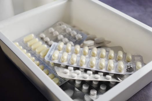 Various organized blister packs of medication neatly arranged in a clean white drawer