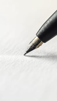 Close-up of a fountain pen poised above blank paper.