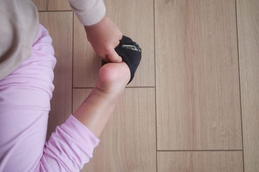 a little girl trying to take off her socks ,