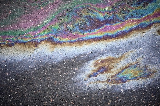 An oil slick forming on a wet asphalt road highlights the problem of pollution in urban areas
