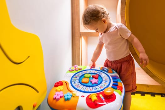 Young child engaged with educational activity table in bright and playful daycare environment