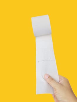 Hand Holding a Roll of Toilet Paper on yellow background