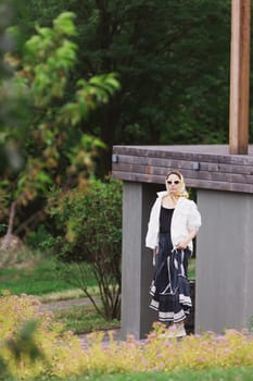 Fashion outdoor photo of beautiful young woman looking like elegant lady,wearing white jacket and accessories. Scarf trendy fashion accessory season