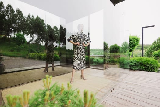 High fashion photo of a beautiful elegant young woman in a pretty zebra print dress posing outdoor. Slim figure.