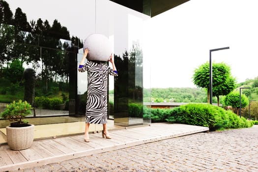 High fashion photo of a beautiful elegant young woman in a pretty zebra print dress posing outdoor. Slim figure.