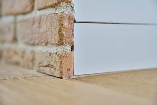 Close-up of a corner, floor plinth inside a wall, edge of a brick wall. Interior elements, design, decor, renovation