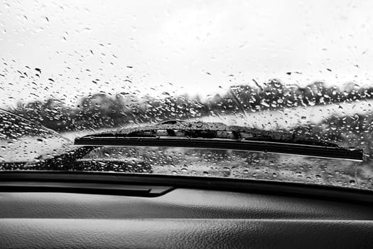 Raindrops on the windshield of a car, view from the inside. Black and white photo