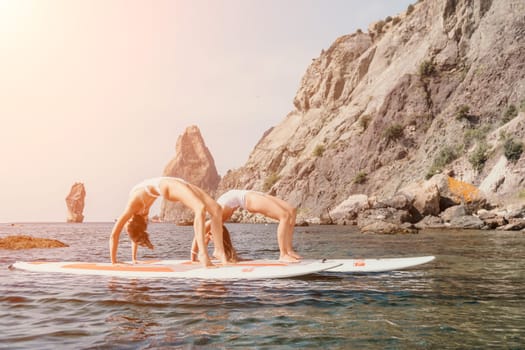 Woman sup yoga. Middle age sporty woman practising yoga pilates on paddle sup surfboard. Female stretching doing workout on sea water. Modern individual hipster outdoor summer sport activity