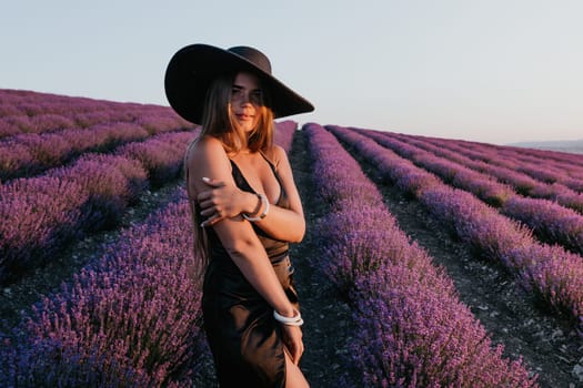 Close up portrait of young beautiful woman in a white dress and a hat is walking in the lavender field and smelling lavender bouquet.