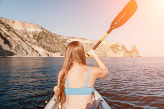 Woman in kayak back view. Happy young woman with long hair floating in transparent kayak on the crystal clear sea. Summer holiday vacation and cheerful female people relaxing having fun on the boat