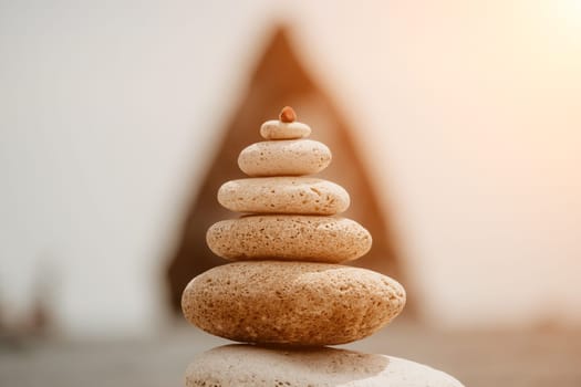 Pyramid stones on the seashore with warm sunset on the sea background. Happy holidays. Pebble beach, calm sea, travel destination. Concept of happy vacation on the sea, meditation, spa, calmness.