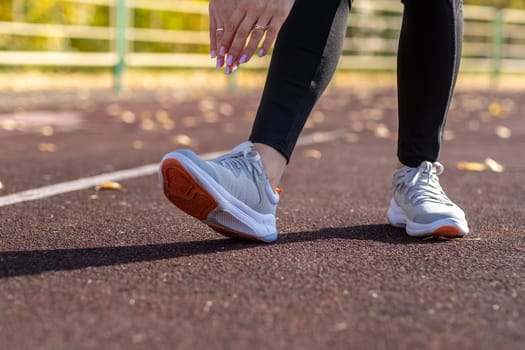 A young beautiful woman in sportswear plays sports at a local stadium. Exercise, jog and exercise at the beginning of the day. Healthy and active lifestyle.