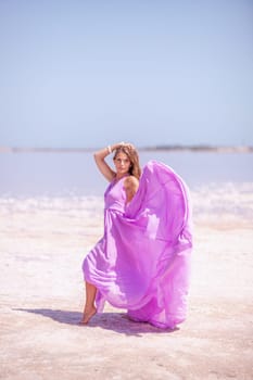 Woman pink salt lake. Against the backdrop of a pink salt lake, a woman in a long pink dress takes a leisurely stroll along the white, salty shore, capturing a wanderlust moment