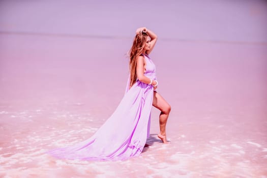 Woman pink salt lake. Against the backdrop of a pink salt lake, a woman in a long pink dress takes a leisurely stroll along the white, salty shore, capturing a wanderlust moment