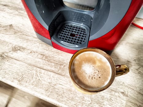 Brewing a fresh cup of coffee using a home machine while enjoying a warm mug on a rustic wooden table.