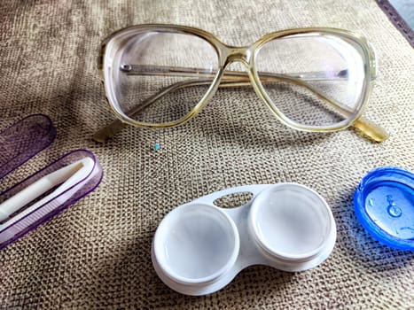 Contact lenses alongside glasses and accessories on a textured background highlight the importance of eye health and vision correction.