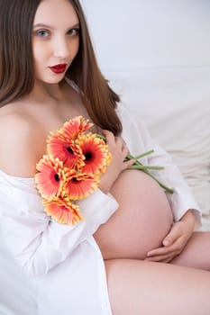 A stunningly beautiful pregnant model gracefully holding vibrant flowers, all captured in a soft, serene setting