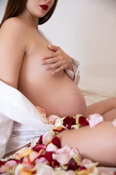 A stunning and artistic portrayal of the beauty of pregnancy featuring delicate rose petals and soft fabric draping