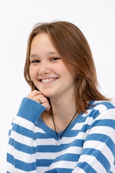 A cheerful young girl poses playfully with a confident smile while wearing a blue and white striped sweater