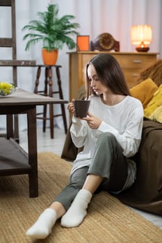 Enjoying a serene moment of deep relaxation indoors while sipping a steaming cup of tea in comfortable attire