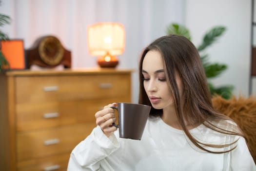 In a serene moment, a woman is savoring her delicious coffee while relaxing in a warm, inviting living space