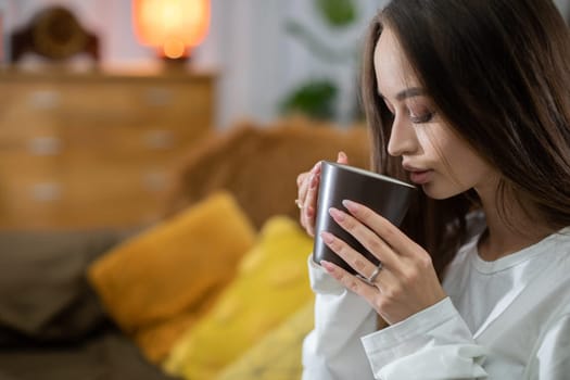 A peaceful and serene scene featuring a woman savoring a warm beverage in a comfortably relaxed setting