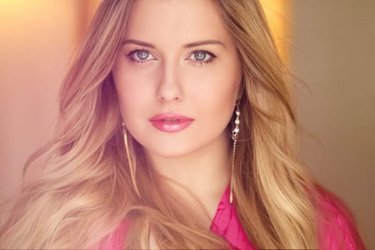 Woman with blue eyes and long, voluminous blonde hair styled in soft curls, wearing pink dress and elegant earrings, dreamy and feminine look idea