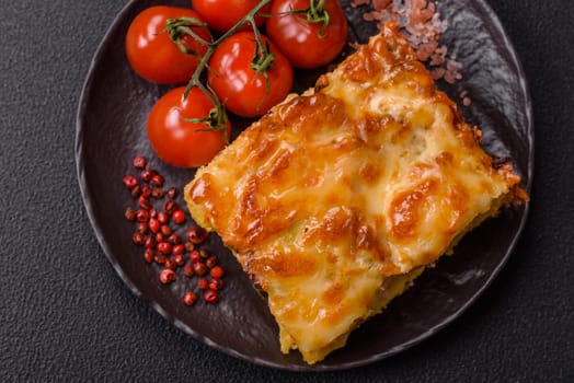 Lasagna or pasta layered with meat, cheese, salt, spices and herbs on dark concrete background