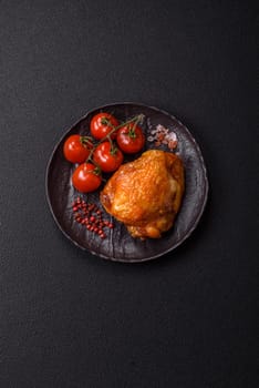 Delicious juicy chicken thighs baked with salt, spices and herbs in a ceramic plate on a dark concrete background