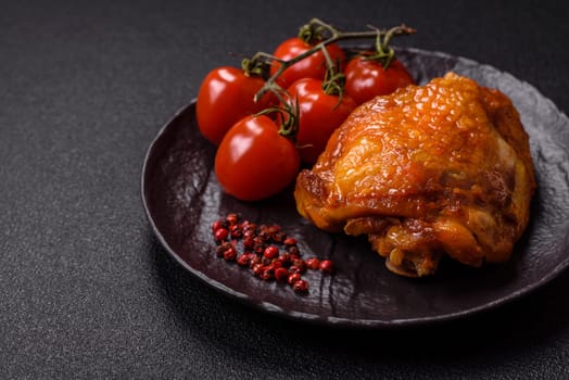 Delicious juicy chicken thighs baked with salt, spices and herbs in a ceramic plate on a dark concrete background