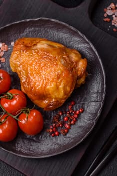 Delicious juicy chicken thighs baked with salt, spices and herbs in a ceramic plate on a dark concrete background