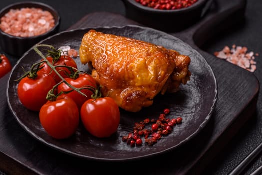 Delicious juicy chicken thighs baked with salt, spices and herbs in a ceramic plate on a dark concrete background