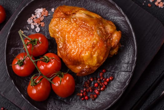 Delicious juicy chicken thighs baked with salt, spices and herbs in a ceramic plate on a dark concrete background