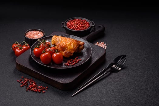 Delicious juicy chicken thighs baked with salt, spices and herbs in a ceramic plate on a dark concrete background