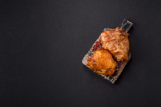 Delicious juicy chicken thighs baked with salt, spices and herbs in a ceramic plate on a dark concrete background