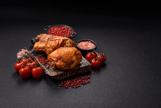 Delicious juicy chicken thighs baked with salt, spices and herbs in a ceramic plate on a dark concrete background
