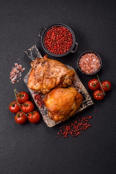 Delicious juicy chicken thighs baked with salt, spices and herbs in a ceramic plate on a dark concrete background
