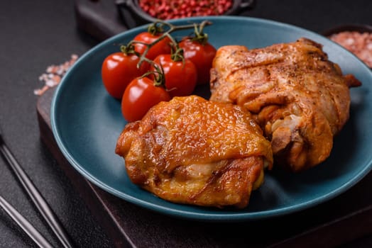 Delicious juicy chicken thighs baked with salt, spices and herbs in a ceramic plate on a dark concrete background