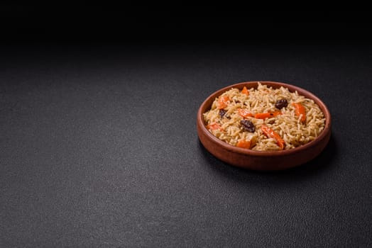 Delicious fresh pilaf with rice, carrots, meat, onions, spices and berries on a ceramic plate on a dark concrete background