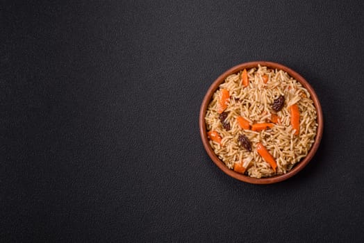 Delicious fresh pilaf with rice, carrots, meat, onions, spices and berries on a ceramic plate on a dark concrete background