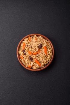 Delicious fresh pilaf with rice, carrots, meat, onions, spices and berries on a ceramic plate on a dark concrete background