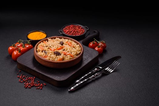 Delicious fresh pilaf with rice, carrots, meat, onions, spices and berries on a ceramic plate on a dark concrete background