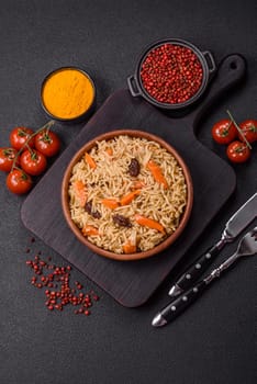 Delicious fresh pilaf with rice, carrots, meat, onions, spices and berries on a ceramic plate on a dark concrete background