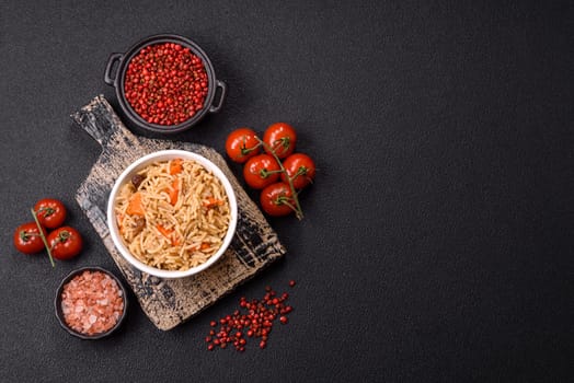 Delicious fresh pilaf with rice, carrots, meat, onions, spices and berries on a ceramic plate on a dark concrete background