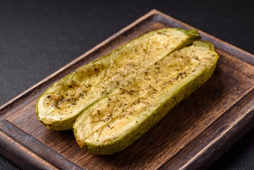 Delicious zucchini cut into two halves baked with salt, spices and herbs on a dark concrete background