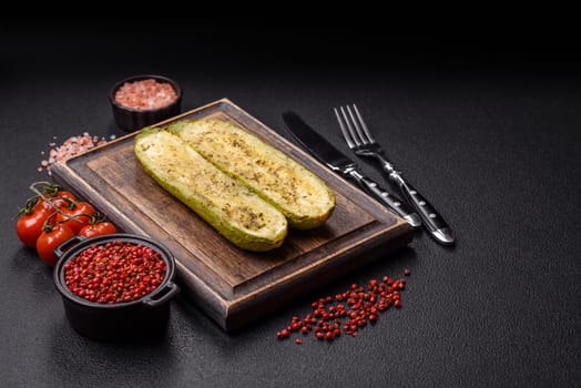 Delicious zucchini cut into two halves baked with salt, spices and herbs on a dark concrete background