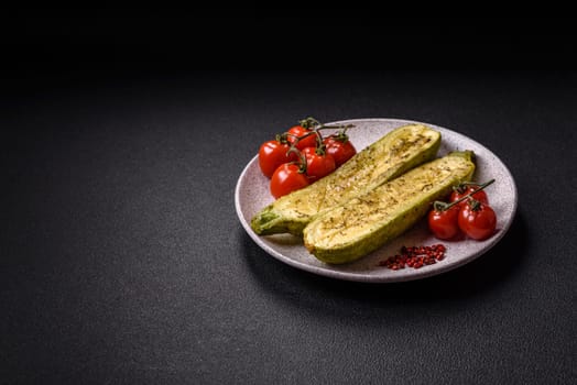 Delicious zucchini cut into two halves baked with salt, spices and herbs on a dark concrete background